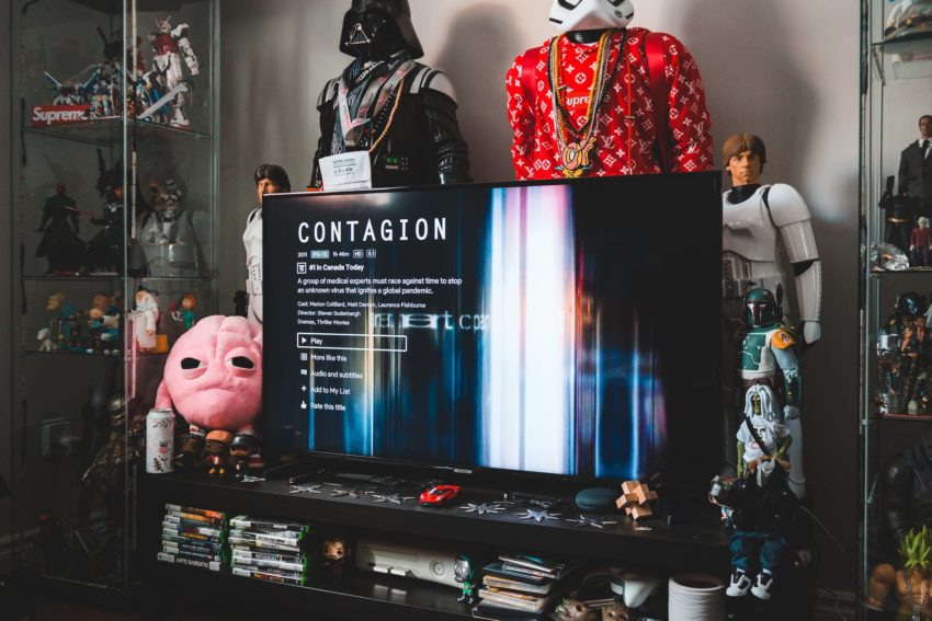 computer with contagion inscription near toy robots and cd collection