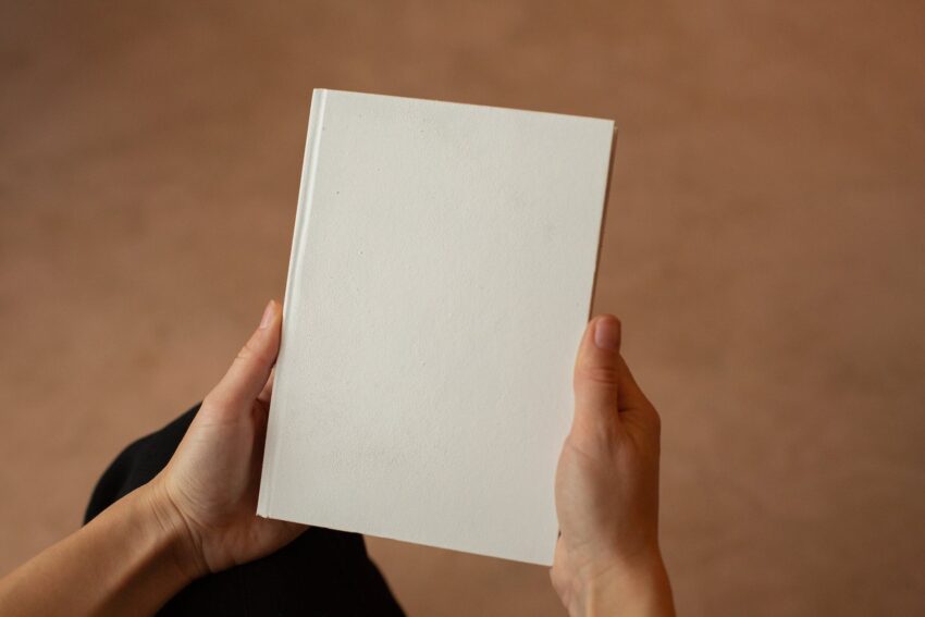 person holding hardcover book with blank cover