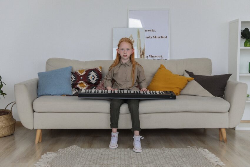 stylish little girl with synthesizer on sofa