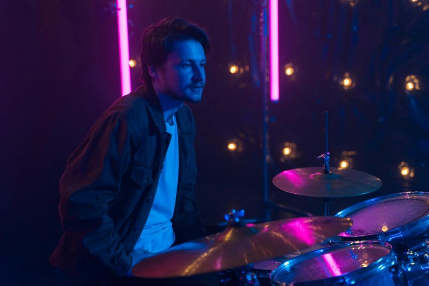 a man sitting in front of a drum set while looking afar